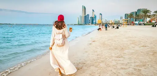 Отдых в Абу-Даби: прогулка по песчаному пляжу на фоне моря и городских небоскребов