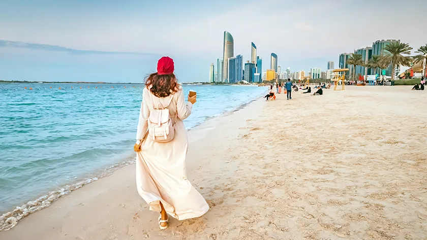 Отдых в Абу-Даби: прогулка по песчаному пляжу на фоне моря и городских небоскребов